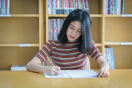 年轻女大学生集中在图书馆内做语言练习考试女学生写考试的练习考图片