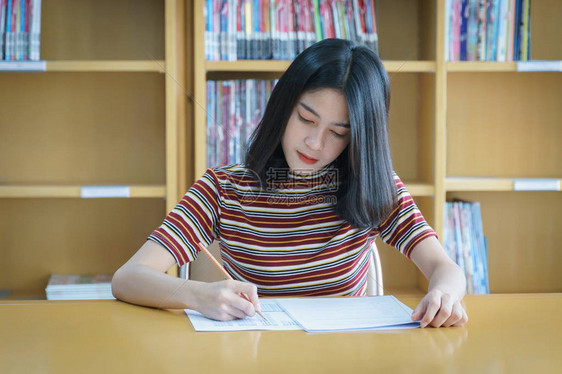 年轻女大学生集中在图书馆内做语言练习考试女学生写考试的练习考图片