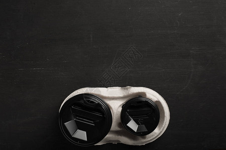 黑色木质背景上的两个一次纸杯咖啡和一个次杯架顶视图概念图片
