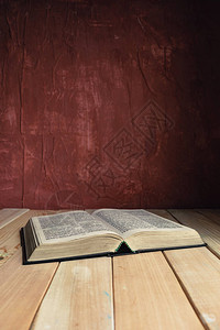 在一张旧木桌上打开圣经美丽的红墙背景背景图片