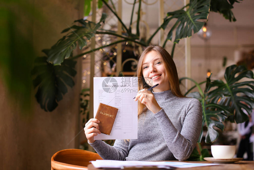 年轻的欧洲高加索妇女填写签证申请并在内阁持有护照图片