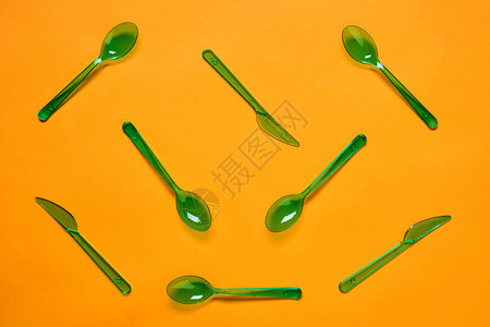 浅橙色背景绿色塑料勺子和叉子的横向平固图片