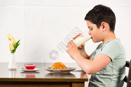 男孩在早餐时喝牛奶的侧视图图片