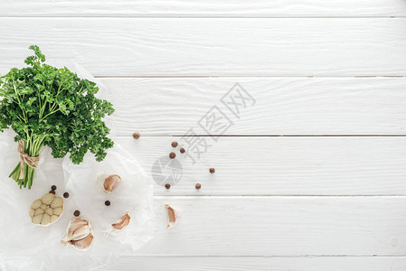 白色木桌上的蒜瓣黑胡椒和欧芹的顶视图图片