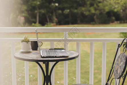 阳台花园林桌边的手提电脑和咖啡图片