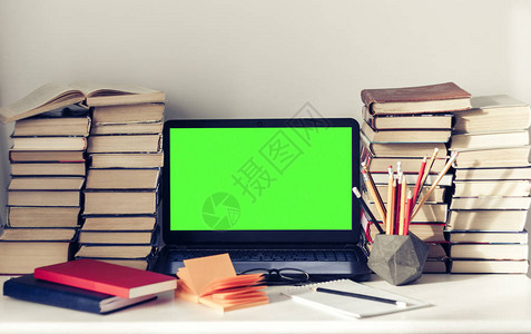 绿色屏幕笔记本电脑堆叠书籍笔记本和白桌上铅笔教育办图片