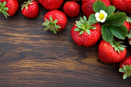 红色草莓和棕色木制背景上的花图片