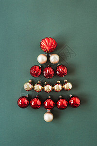 圣诞树符号由绿色背景上的红色和金色圣诞小玩意球制成图片