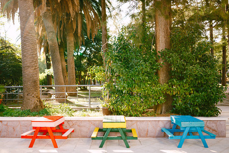 三张桌子和不同颜色的长凳公园里的街头家具红色绿色黄背景图片