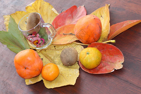 杯子里的水果和五颜六色的树叶上的静物图片