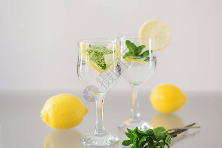 柠檬和薄荷柠檬水玻璃桌上放着新鲜薄荷柠檬水果和苏打矿泉图片