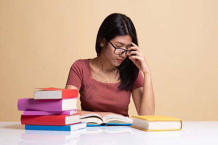 疲惫的亚裔妇女头痛读一本书上面有关于图片