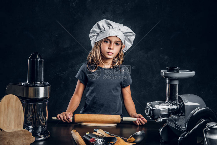戴厨师帽的小穿笔小姑娘正在给带厨房设备的图片