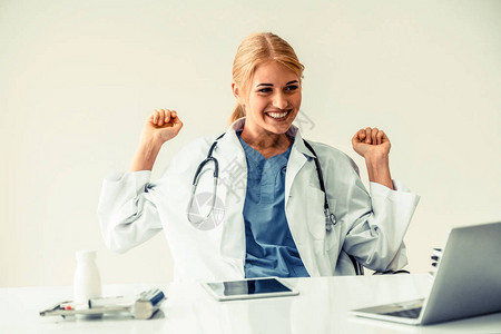 快乐的成功女医生在医院或医疗机构工作时在办公桌上写医疗报告时感到很愉快背景图片