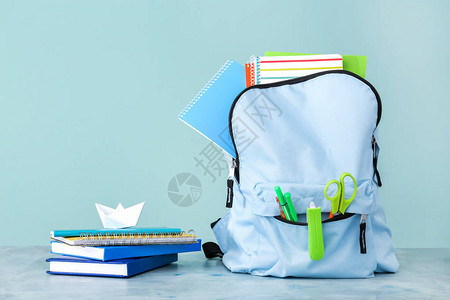 彩色背景下桌子上的学校背包和文具图片