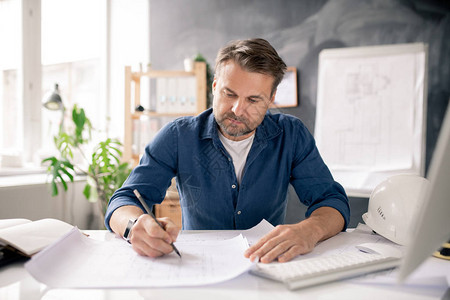 认真的成熟建筑师在办公室电脑面前坐在办公桌前图片