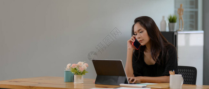 女教授在客厅数字平板电脑工作时通过电话与学生交谈的裁剪图片