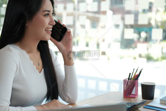 女商人在办公室谈智能手机年轻的亚洲自由职业女企业家使用手图片