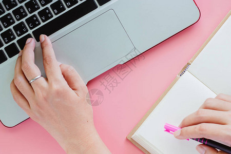 女手用电脑笔记本电脑和持笔以粉色背景图片
