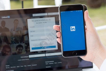 商人拿着iphone6s与社交网络服务LinkedIn在屏幕上iPhone由AppleInc图片