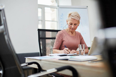 在办公室工作的成熟女老板坐在会议室桌旁的肖图片素材
