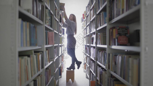 年轻女学生从大学图书馆的书架图片