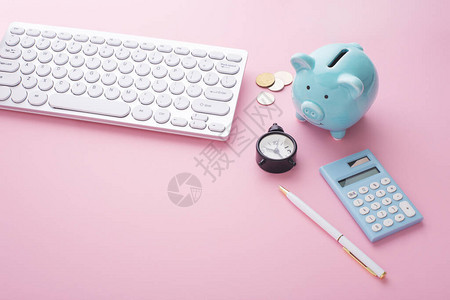 粉色桌上带有小猪银行计算器和硬币图片