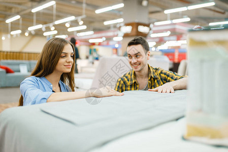年轻快乐的夫妇在家具店买床品图片