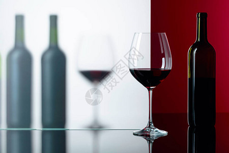 黑色反射背景上的红酒瓶和杯子您的自由空间图片