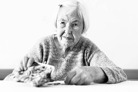 忧心忡的96岁老妇人坐在家里的餐桌旁图片
