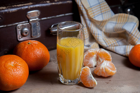 几个未去皮的全鲜橙橘子或橙子橘子柑桔柑橘类水果去皮的橘子片和一杯新鲜果图片