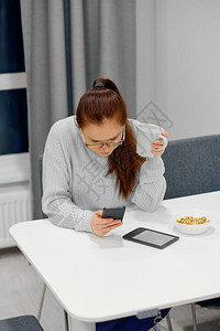 身穿灰色针织毛衣的年轻白种女人坐在现代浅色室内的餐桌旁图片