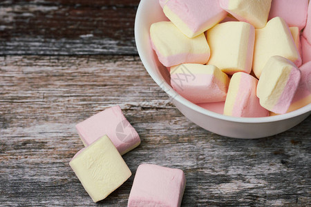粉色和黄色棉花糖在木质表面的白碗中图片