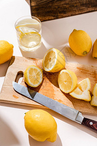 木板上用刀子和杯子在灰色桌子上浇满整片柠檬图片