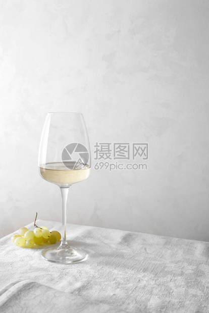 白葡萄酒在杯子里桌子上有一堆葡图片