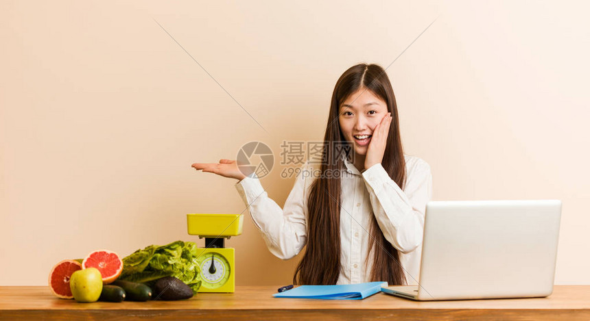 利用笔记本电脑工作的年轻营养主义者女在手掌上拥有复制空间图片