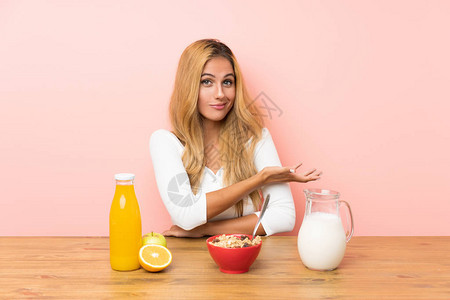 喝早餐牛奶的金发年轻女青年把手伸到旁边图片