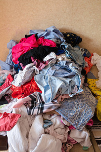 五颜六色的幼稚衣服散落在家里的沙发上的正面图一大堆衣服在洗衣前躺在房间里清洁混乱泥土图片