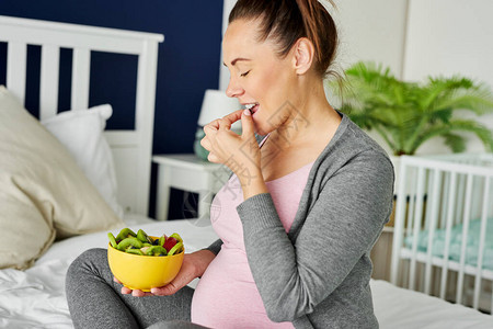 吃一碗水果的快乐的孕妇图片