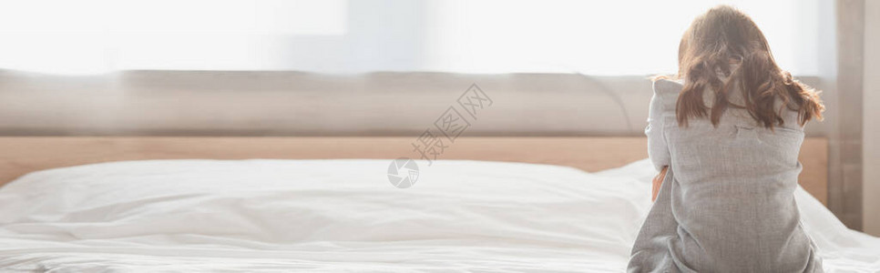 压抑的黑发女人坐在床背景图片