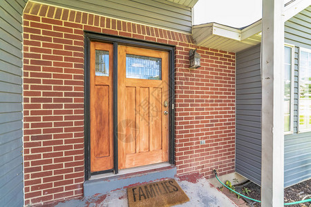 家有砖和木墙部分和玻璃镶板的前门和侧灯门口台阶处可以看到门垫和图片