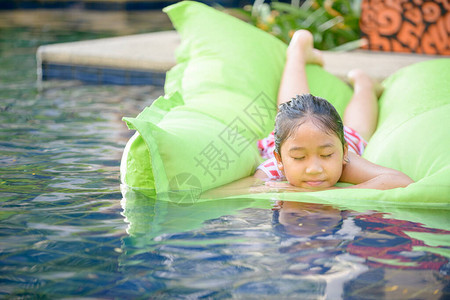 可爱的小女孩在游泳池玩空气床垫图片
