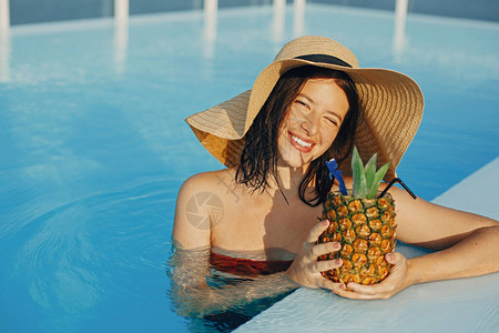 美丽的年轻女子微笑着喝菠萝鸡尾酒图片