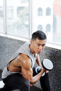 在健身房里用哑铃做运动的越南男图片