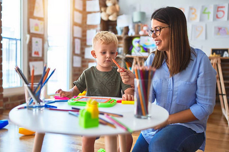 年轻的白种人孩子和老师在幼儿园玩耍母子在游戏室图片