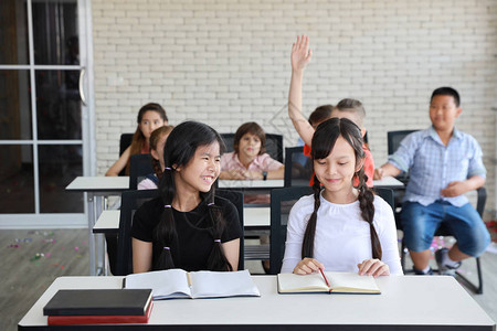 多民族活跃的学校女孩和男孩穿着休闲装坐在学校习聪明的孩子在课堂上举手图片