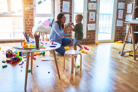 年轻的白种人孩子和老师在幼儿园玩耍母子在游戏室里玩图片