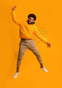 穿着冬季夹克的欢乐Afro的家伙在橙色背景图片