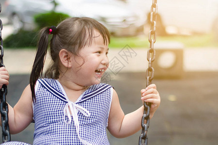 白皮肤的亚洲黑头发女孩在游乐场玩耍时笑得非常开心背景图片