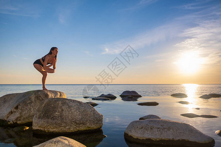 全身瘦的雌手握在宁静海边岩石上平衡在晚图片